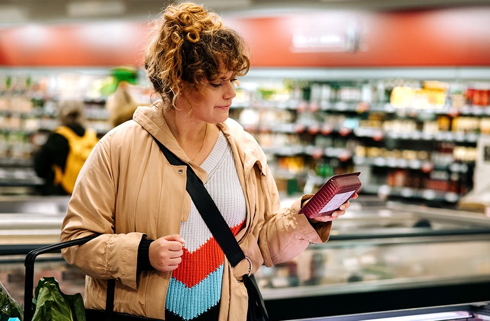 Mulher olhando etiqueta a prova d' água de comida congelada